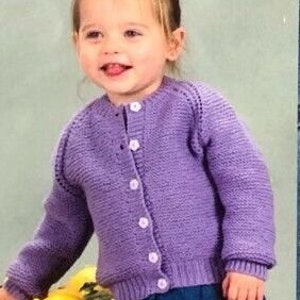 May include: A purple knitted cardigan with a button closure. The cardigan has a round neckline and long sleeves.