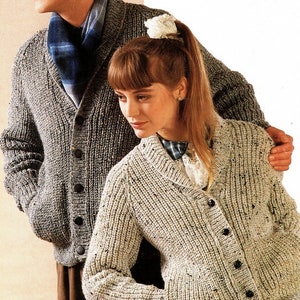 May include: Two knitted cardigans, one in grey with a blue scarf and one in beige. Both cardigans have a shawl collar and button closure.