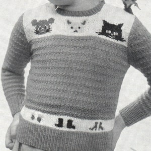 May include: A gray knitted sweater with a white band across the chest featuring a cat, a bunny, and a mouse. The sweater has a white band at the bottom with a design of two boots and the letters "JL".