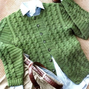 May include: A green crocheted cardigan with a button-up front and long sleeves. The cardigan is made with a cable stitch pattern.