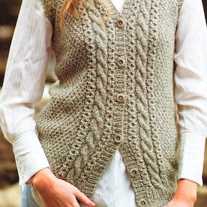 Può includere: Un gilet di maglia beige con un motivo a treccia e chiusura con bottoni.