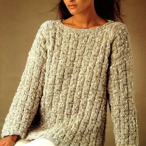 May include: A beige knitted jumper with a textured pattern. The jumper has a round neckline and long sleeves.