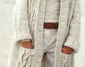 Könnte beinhalten: Ein langer, cremefarbener Strickcardigan mit Zopfmuster und zwei Taschen. Der Cardigan hat einen Kragen und eine lange, offene Vorderseite.