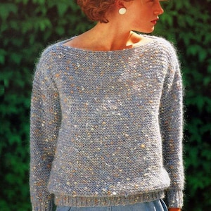 May include: A light blue sweater with a speckled pattern. The sweater has a boat neck and long sleeves.