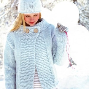 May include: A light blue knitted cardigan with a button closure and a matching light blue knitted hat. The cardigan has a slightly oversized fit and a relaxed silhouette. The model is wearing the cardigan with a striped shirt and white pants.