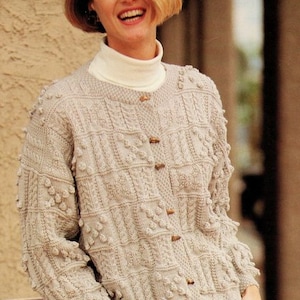 Może przedstawiać: Beżowy kardigan dzianinowy z zapięciem na guziki i fakturowanym wzorem. Kardigan ma okrągły dekolt i długie rękawy.