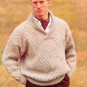 May include: A beige knitted sweater with a shawl collar and a diamond pattern. The sweater has a button closure at the neck.