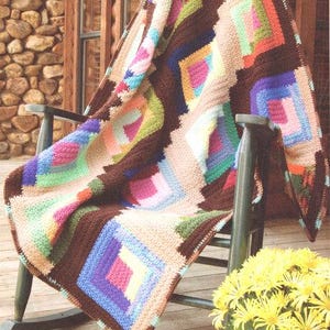 May include: A colorful, handmade quilt draped over a wooden rocking chair. The quilt features a geometric pattern with squares and diamonds in shades of brown, beige, pink, blue, green, and purple. The text in the image says, "An old-fashioned quilt pattern makes good use of leftover yarn."