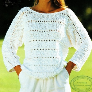 May include: White crocheted sweater with a loose fit and a boat neck. The sweater has a delicate openwork pattern with small bobbles throughout.