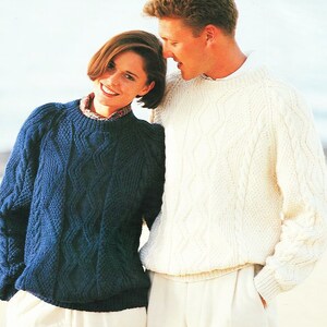 May include: A couple wearing matching cable knit sweaters. The woman's sweater is blue and the man's sweater is white.