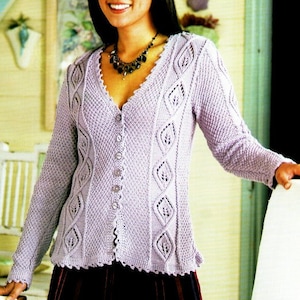 Peut inclure: Un cardigan en tricot de couleur lilas clair avec un col en V, une fermeture boutonnée et des motifs complexes en forme de feuilles. Le cardigan a un ourlet festonné et est porté sur une jupe noire.
