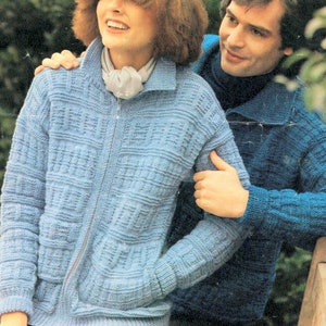 Può includere: Una coppia indossa maglioni di lana. La donna indossa un maglione blu chiaro con una cerniera e una sciarpa bianca. L'uomo indossa un maglione blu scuro con un colletto.