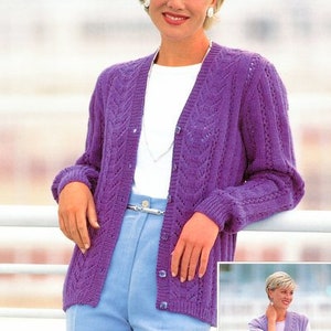 May include: A purple knitted cardigan with a V-neck and a button closure. The cardigan has a cable knit pattern and is worn over a white t-shirt and blue jeans.