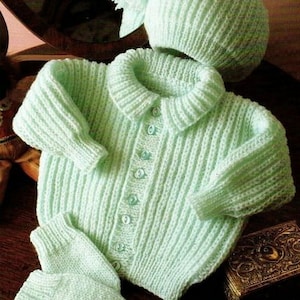 May include: A light green knitted baby cardigan, hat and mittens set. The cardigan has a button fastening and a collar. The hat has a pom-pom on top.