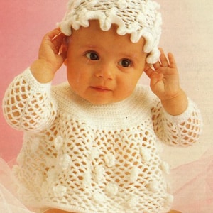 May include: A white crocheted baby outfit with a matching hat. The outfit features a lacy design with small white pom-poms.