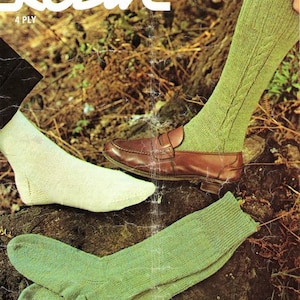 May include: A pair of green socks with a ribbed texture, and a pair of white socks. The socks are laid out on a brown surface. The image also shows a brown leather loafer with a green sock on the foot. The image includes the text "Robin 2590 4 Ply".