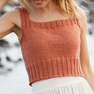 May include: A terracotta-colored knitted tank top with a square neckline and thin straps. The top is cropped and has a ribbed hem.