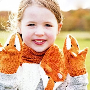May include: A young girl wearing a knitted fox scarf and matching mittens. The scarf and mittens are orange with white accents and feature fox faces.