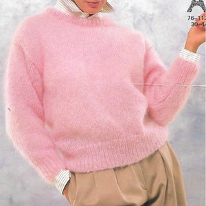 Könnte beinhalten: Ein flauschiger rosa Pullover mit Rundhalsausschnitt. Der Pullover ist aus weichem, flauschigem Garn gefertigt und hat eine lockere Passform.