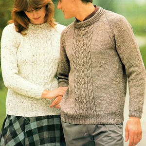 May include: Two people wearing knitted jumpers. The person on the left is wearing a white jumper with a cable knit pattern. The person on the right is wearing a brown jumper with a cable knit pattern.