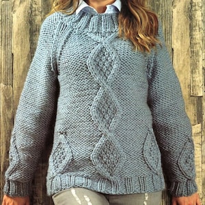 May include: A light blue knitted sweater with a cable knit pattern. The sweater has a round neckline and long sleeves.