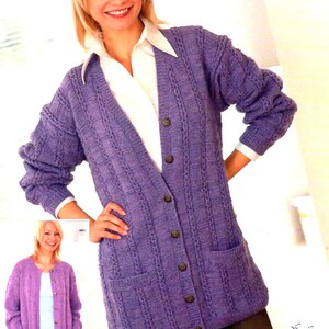 May include: A purple knitted cardigan with a cable knit pattern and button closure. The cardigan has two pockets and is shown being worn by a model. The text "Includes Larger Sizes" is visible in the bottom right corner of the image.