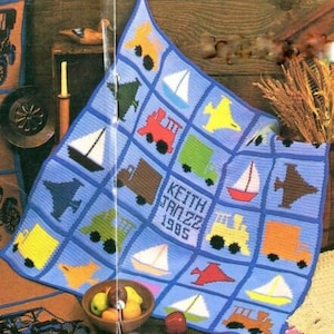 Könnte beinhalten: Eine blaue gehäkelte Babydecke mit einer Vielzahl von bunten Quadraten, die verschiedene Fahrzeuge, Segelboote und Flugzeuge zeigen. Die Decke ist mit dem Namen "Keith Jan 22 1985" personalisiert.