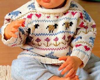 Könnte beinhalten: Ein cremefarbener Baby-Pullover mit hohem Kragen, der ein Muster aus Schafen, Herzen und floralen Designs in Rosa, Blau und Braun aufweist. Der Pullover wird mit einer hellblauen Hose kombiniert.
