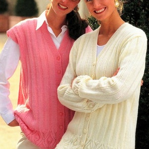 May include: Two women wearing knitted sweaters. One woman is wearing a pink sleeveless sweater with a button-up front. The other woman is wearing a white cardigan with a button-up front. Both sweaters have a cable knit pattern.