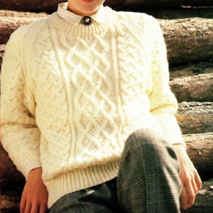 May include: A white cable knit jumper with a crew neck and long sleeves. The jumper features a detailed cable knit pattern.