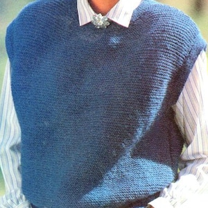 May include: A blue knitted vest over a striped shirt, paired with blue pants and a brown belt with a gold buckle. The vest has a textured knit pattern. A decorative brooch is pinned to the collar.