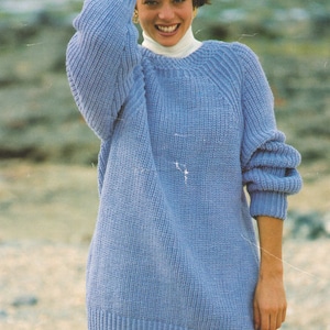May include: A light blue knitted sweater with a round neckline. The sweater is loose fitting and has long sleeves.