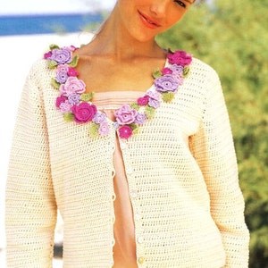 May include: A white crocheted cardigan with a floral design around the neckline. The flowers are crocheted in shades of pink, purple, and green.