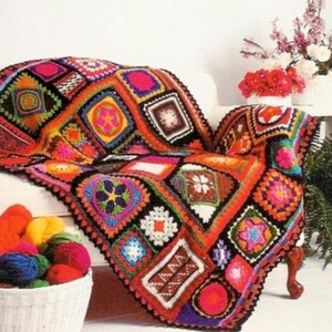 Peut inclure: Une couverture en crochet colorée avec un motif patchwork composé de carrés de différentes couleurs et motifs. La couverture est posée sur un canapé blanc et a une bordure noire.