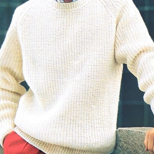 May include: A white knitted sweater with a round neckline and long sleeves. The sweater has a ribbed texture and a relaxed fit.