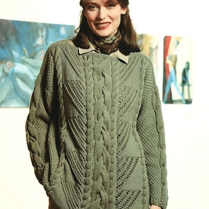 Può includere: Un maglione verde a treccia con un motivo a treccia dettagliato. Il maglione ha un collo a V e maniche lunghe.