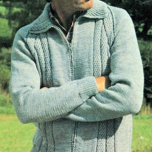 Può includere: Un cardigan di maglia blu chiaro con chiusura a zip e un motivo a treccia. Il cardigan ha un colletto e maniche lunghe.