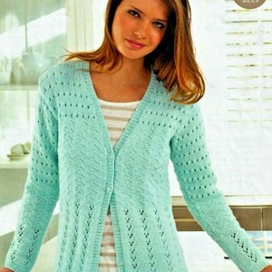 May include: A light blue knitted cardigan with a delicate openwork pattern. The cardigan has a V-neck and long sleeves. It is shown on a model wearing a striped shirt underneath.