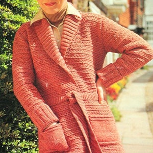 May include: A long-sleeved, rust-colored cardigan with a shawl collar, a tie belt, and two patch pockets. The cardigan is knitted in a textured stitch.