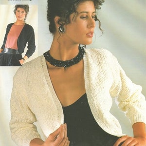 Könnte beinhalten: Ein weißer Strickcardigan mit V-Ausschnitt und langen Ärmeln. Der Cardigan wird von einem Model mit einem schwarzen Oberteil darunter getragen. Der Text "chenille and Double knittings" ist in der oberen linken Ecke des Bildes sichtbar. Der Text "Easy knit" ist in der oberen rechten Ecke des Bildes sichtbar.