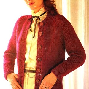 Op de afbeelding: Een rode gebreide cardigan met een knoopsluiting en een wit overhemd met kraag eronder. De cardigan heeft een ronde hals en lange mouwen.
