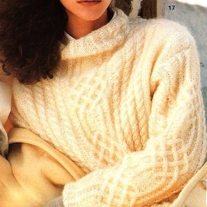 Peut inclure: Pull en maille crème avec un col roulé replié. Le pull présente un motif texturé et des manches longues. Le tricot doux et clair est un style classique.