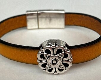 May include: A brown leather bracelet with a silver magnetic clasp and a silver flower charm.