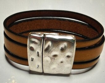 May include: A brown leather bracelet with a silver clasp. The clasp has a textured design.