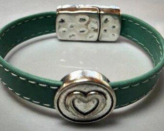 May include: A teal leather bracelet with a silver heart charm and a magnetic clasp.