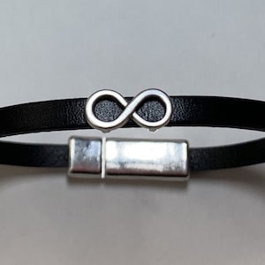 May include: A black leather bracelet with a silver infinity symbol charm and a magnetic clasp.