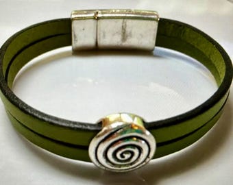 May include: A green leather bracelet with a silver magnetic clasp and a silver spiral charm.
