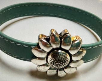 May include: A teal leather bracelet with a silver sunflower charm.