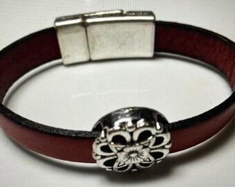 May include: A red leather bracelet with a silver magnetic clasp and a silver flower charm.