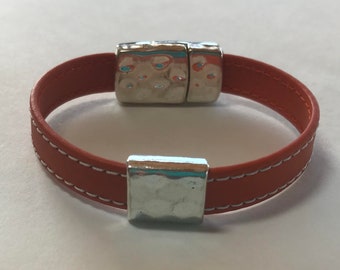 May include: A brown leather bracelet with white stitching and silver magnetic clasps.